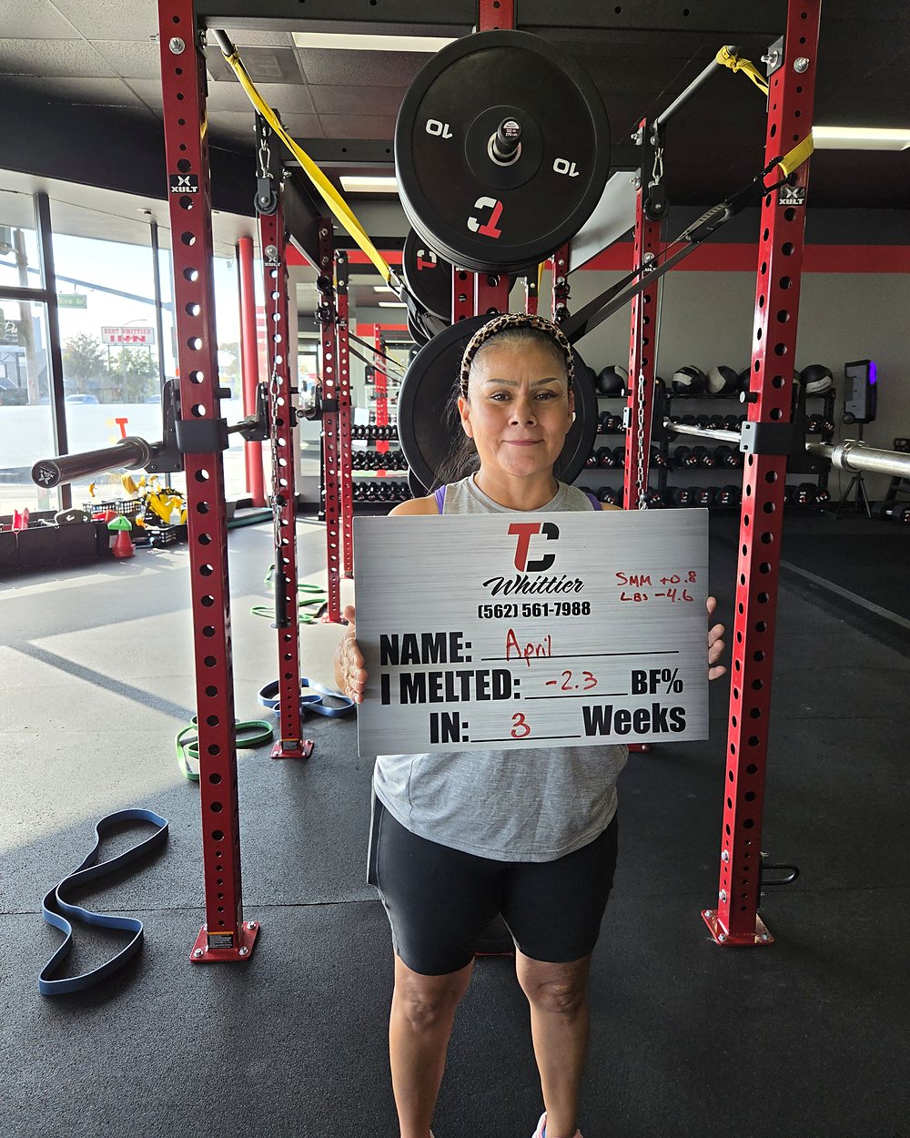 April at a Camp Whittier weigh-in, holding a board that reads: melted 2.3 percent body fat in 3 weeks, and 4.6 pounds.