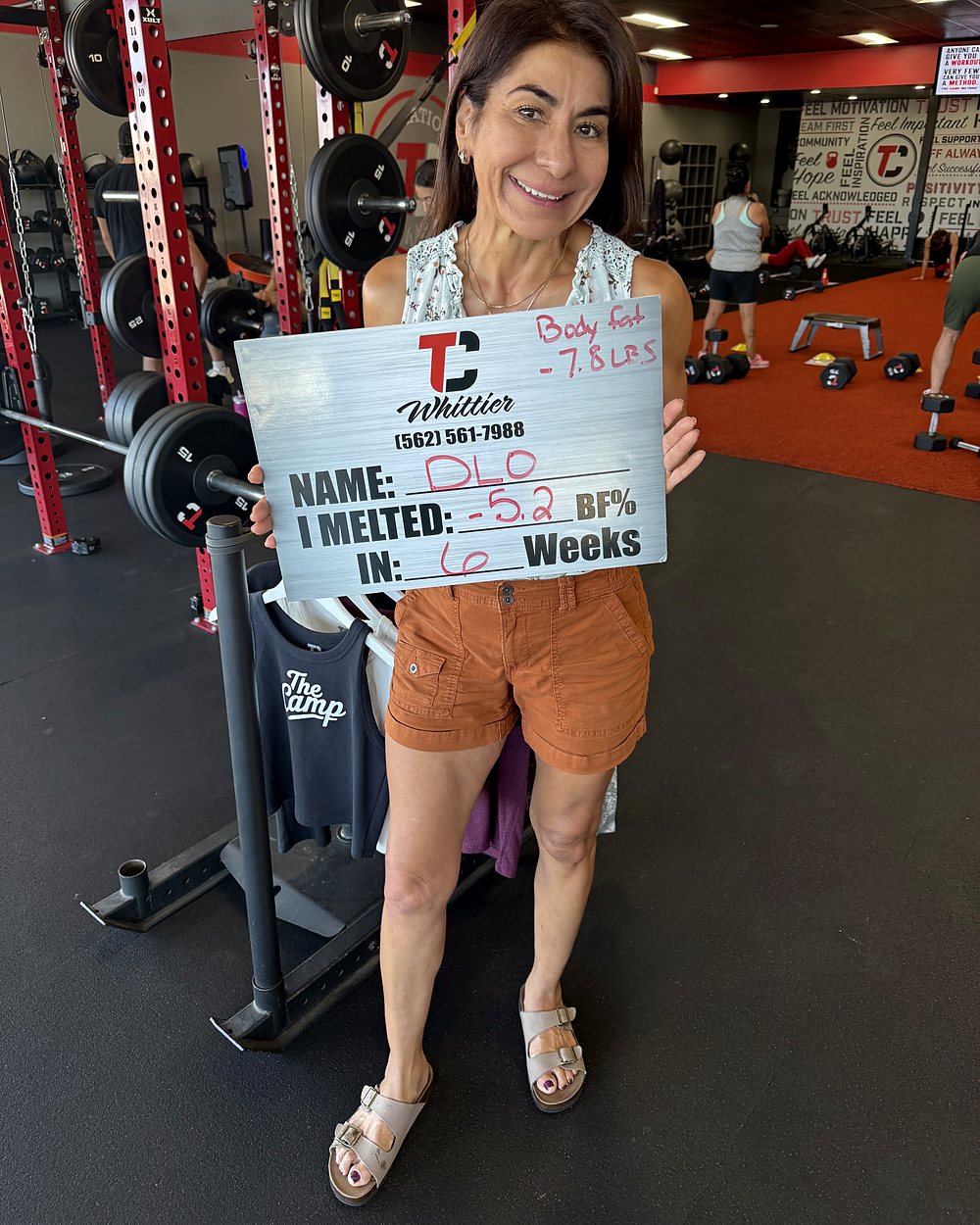 DLO at a Camp Whittier weigh-in, holding a board that reads: melted 5.2 percent body fat in 6 weeks, 7.8 pounds of fat.