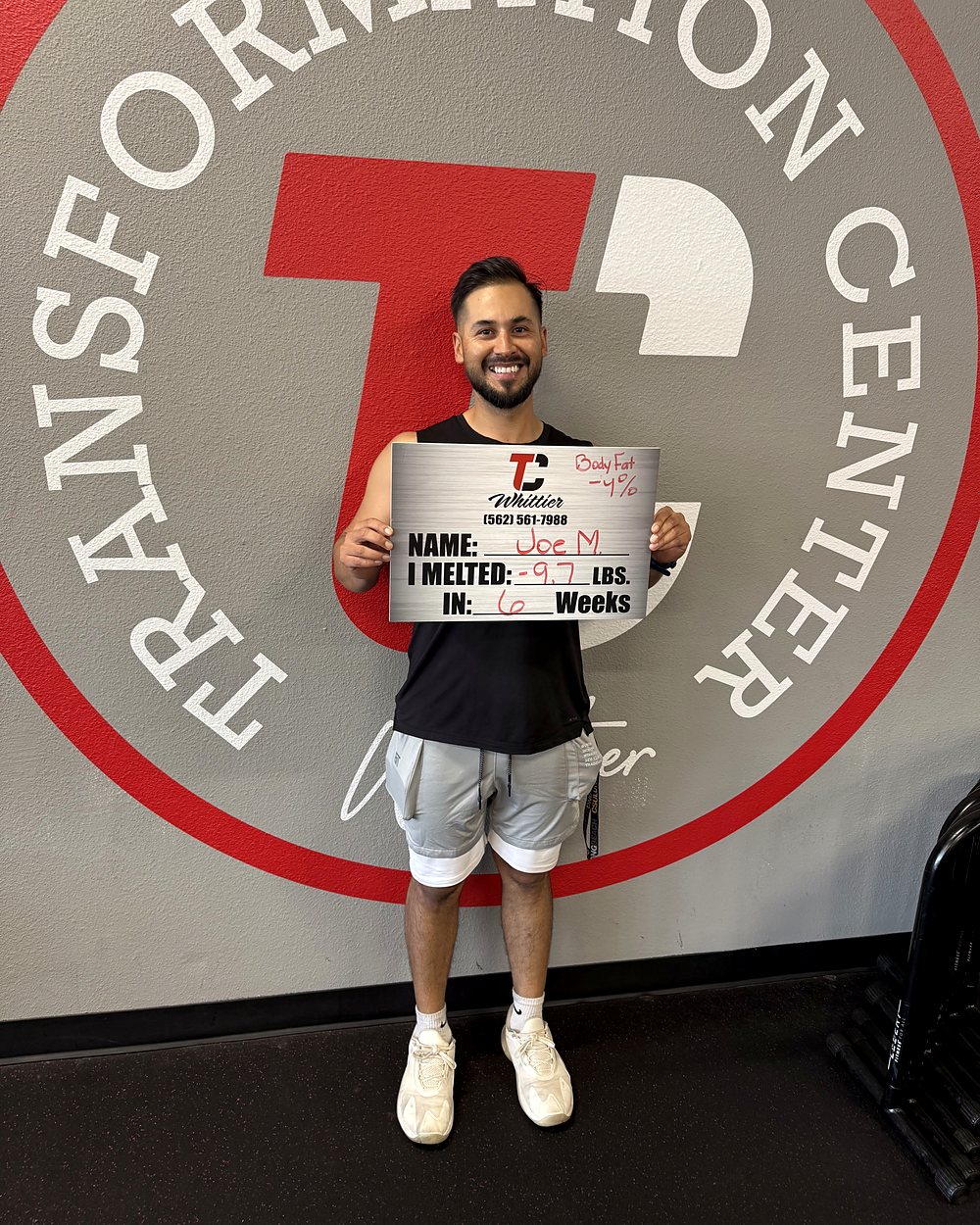 Joe M. at a Camp Whittier weigh-in, holding a board that reads: melted 9.7 pounds in 6 weeks, with body fat down 4 percent.